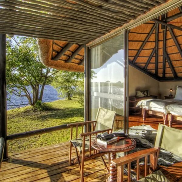 Eine Lodge mit geöffneter Terrassentür, über die man in die grüne Wildnis Botswanas blicken kann